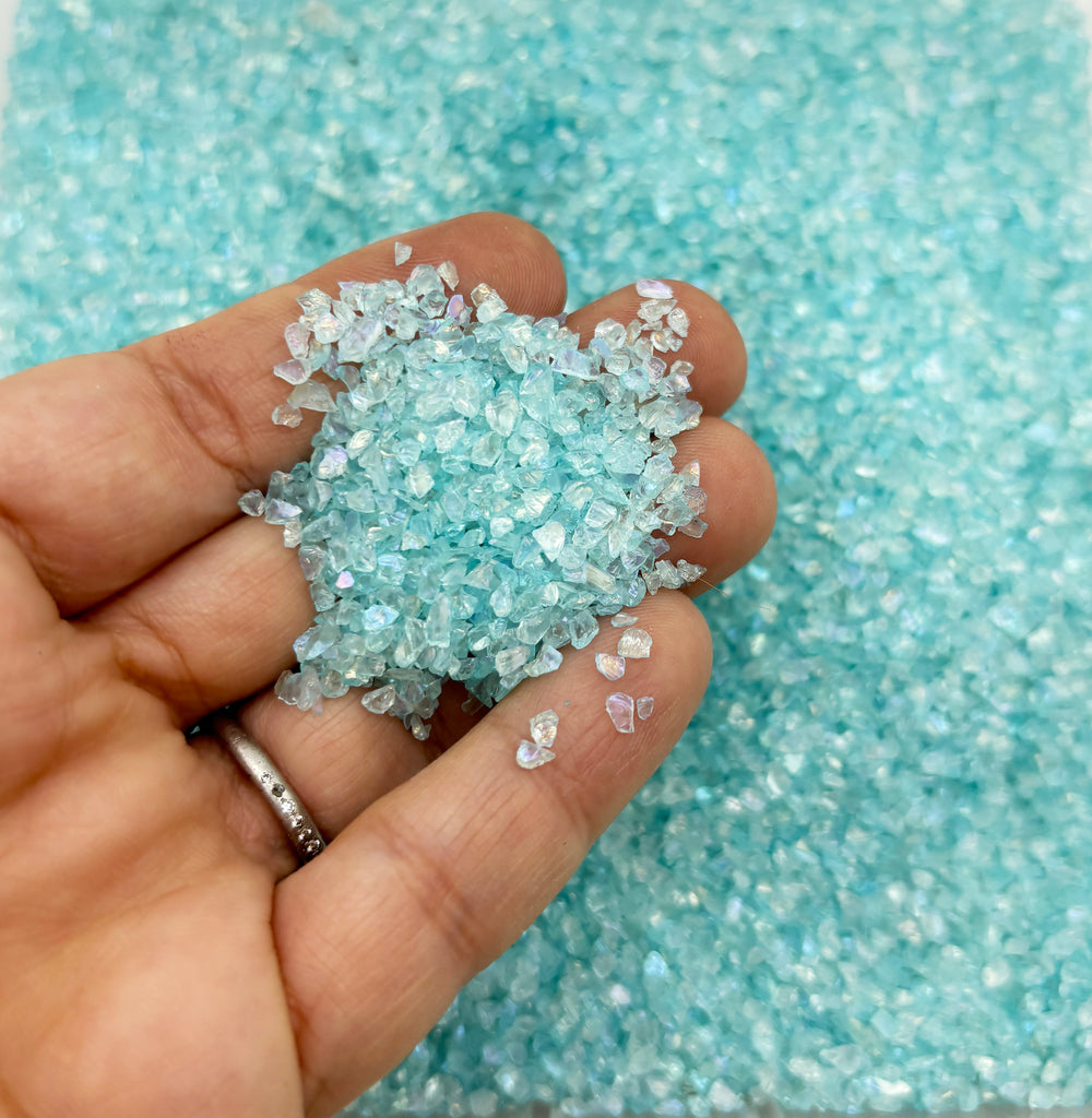 a person holding a small piece of blue glitter