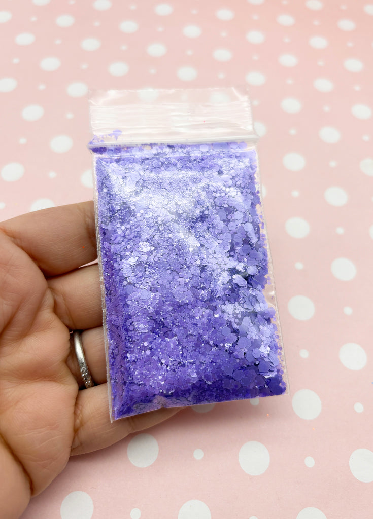 a hand holding a small bag of purple glitter