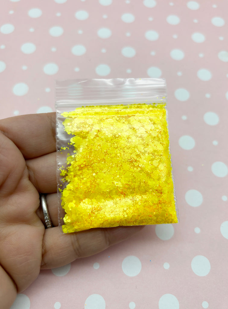 a hand holding a bag of yellow glitter