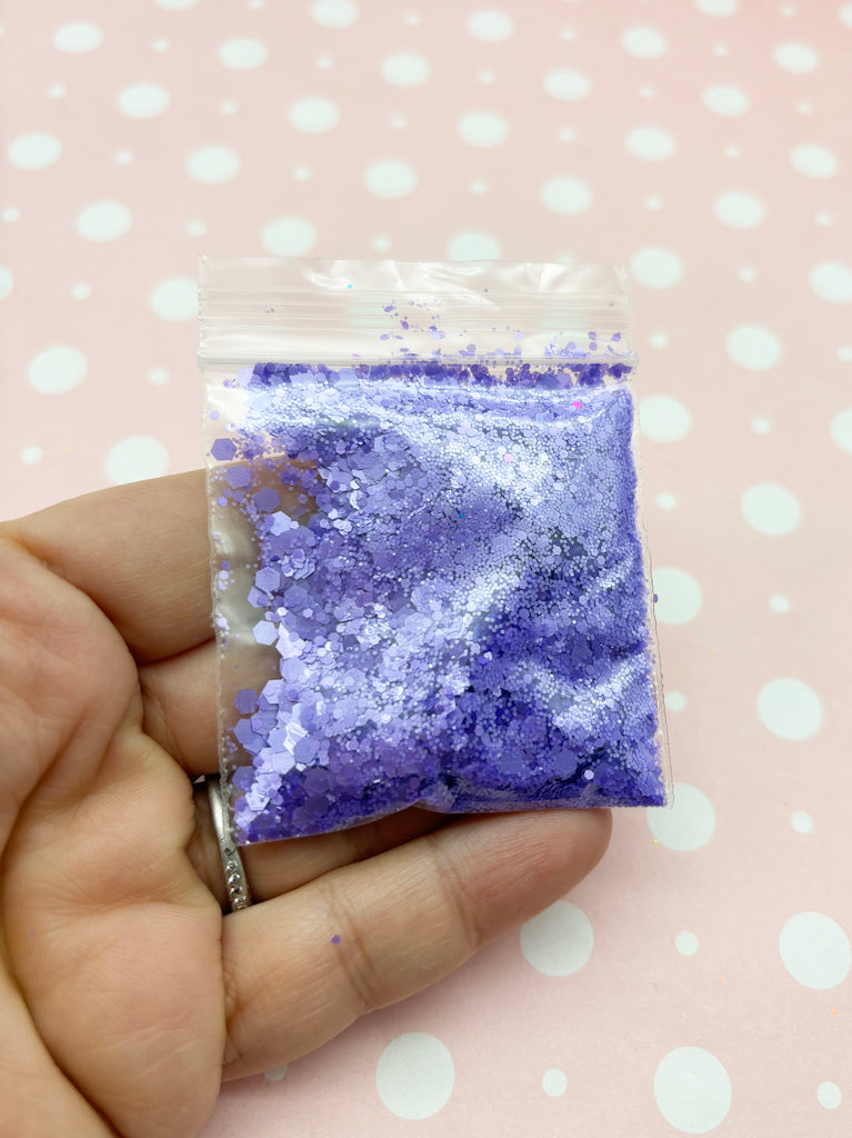 a hand holding a small bag of purple glitter