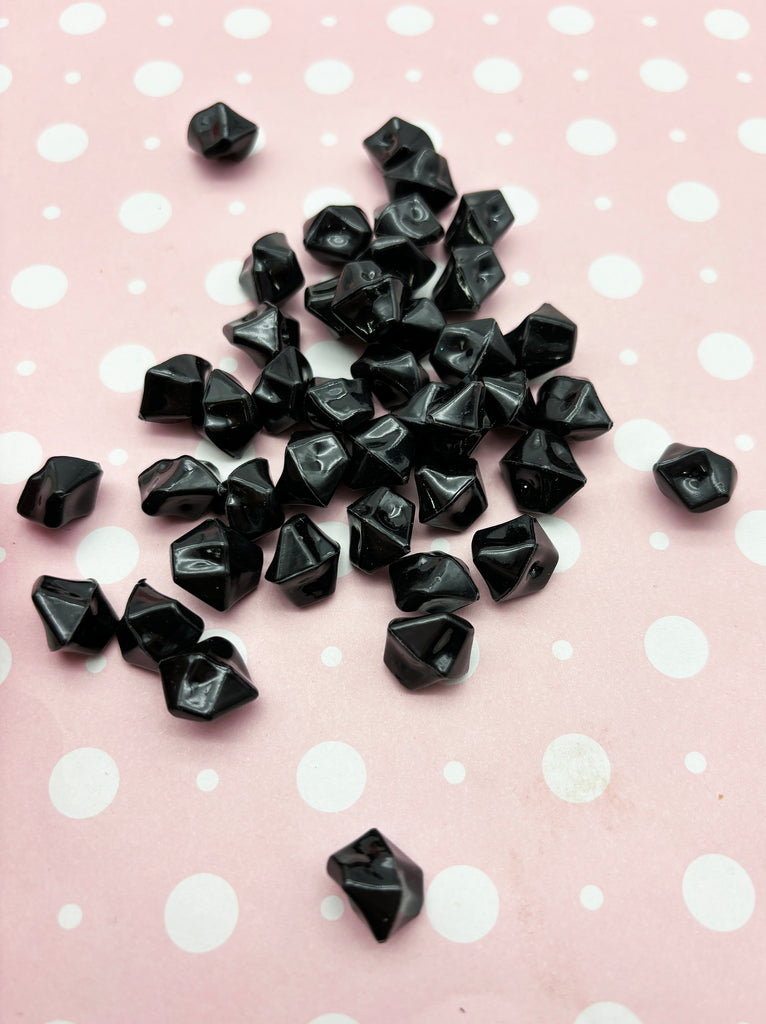 a pile of black beads sitting on top of a pink table