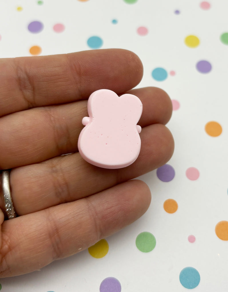 a person holding a pink bear shaped object in their hand